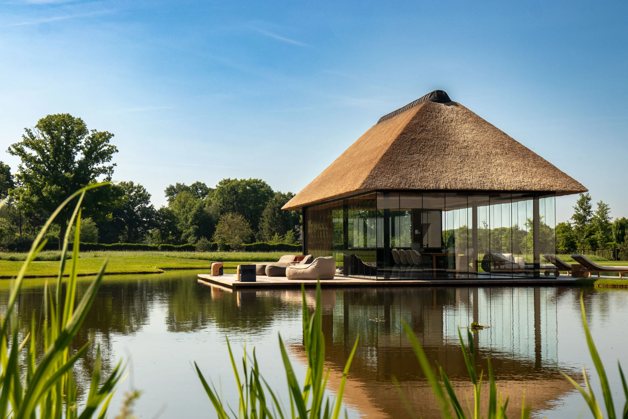 vijver met bijgebouw van riet en glas als eiland