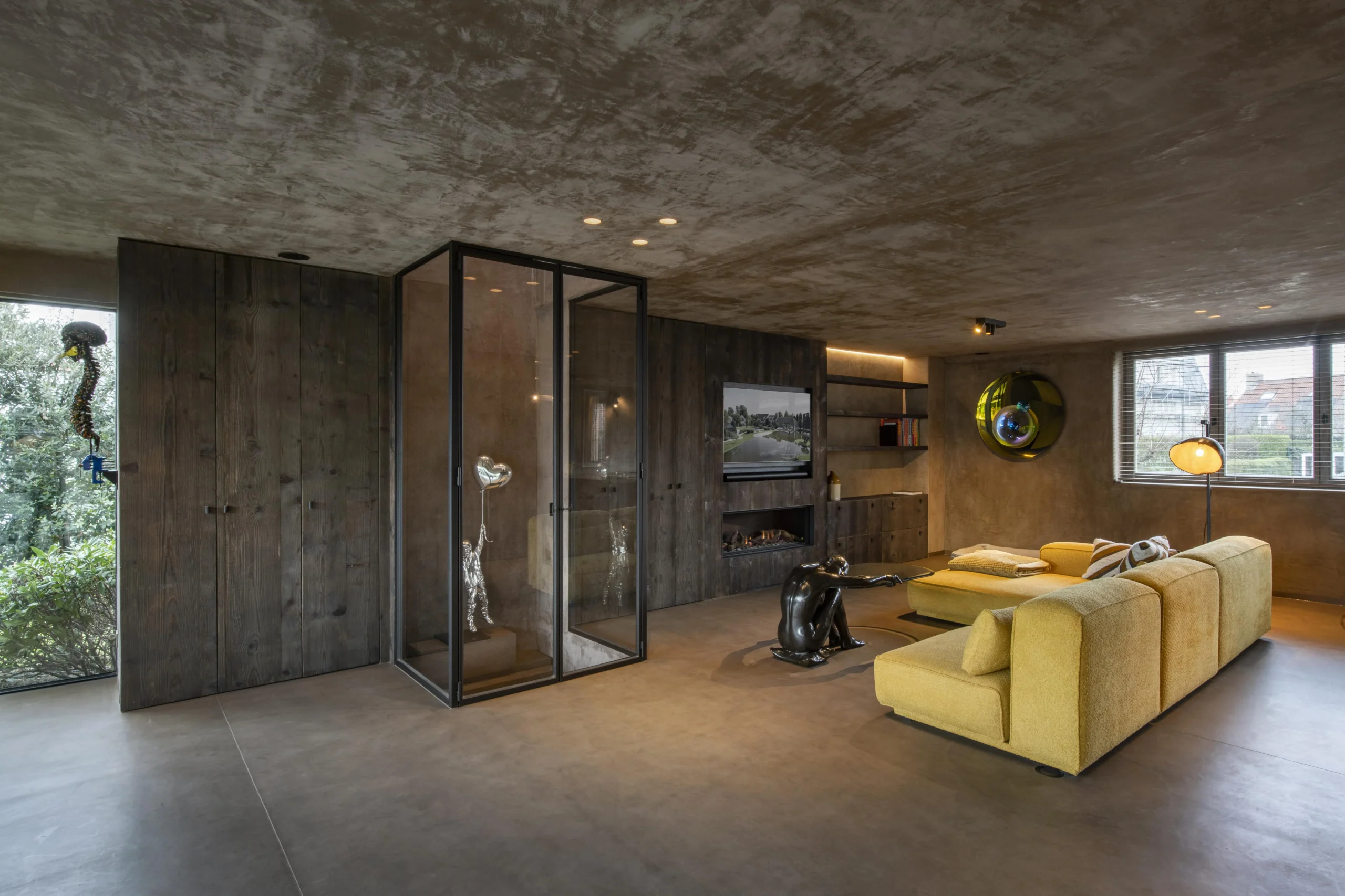 Lounge met glazen wand en natuurlijke materialen.