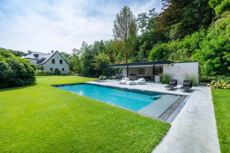 Moderne tuin met strak zwembad in groene omgeving.
