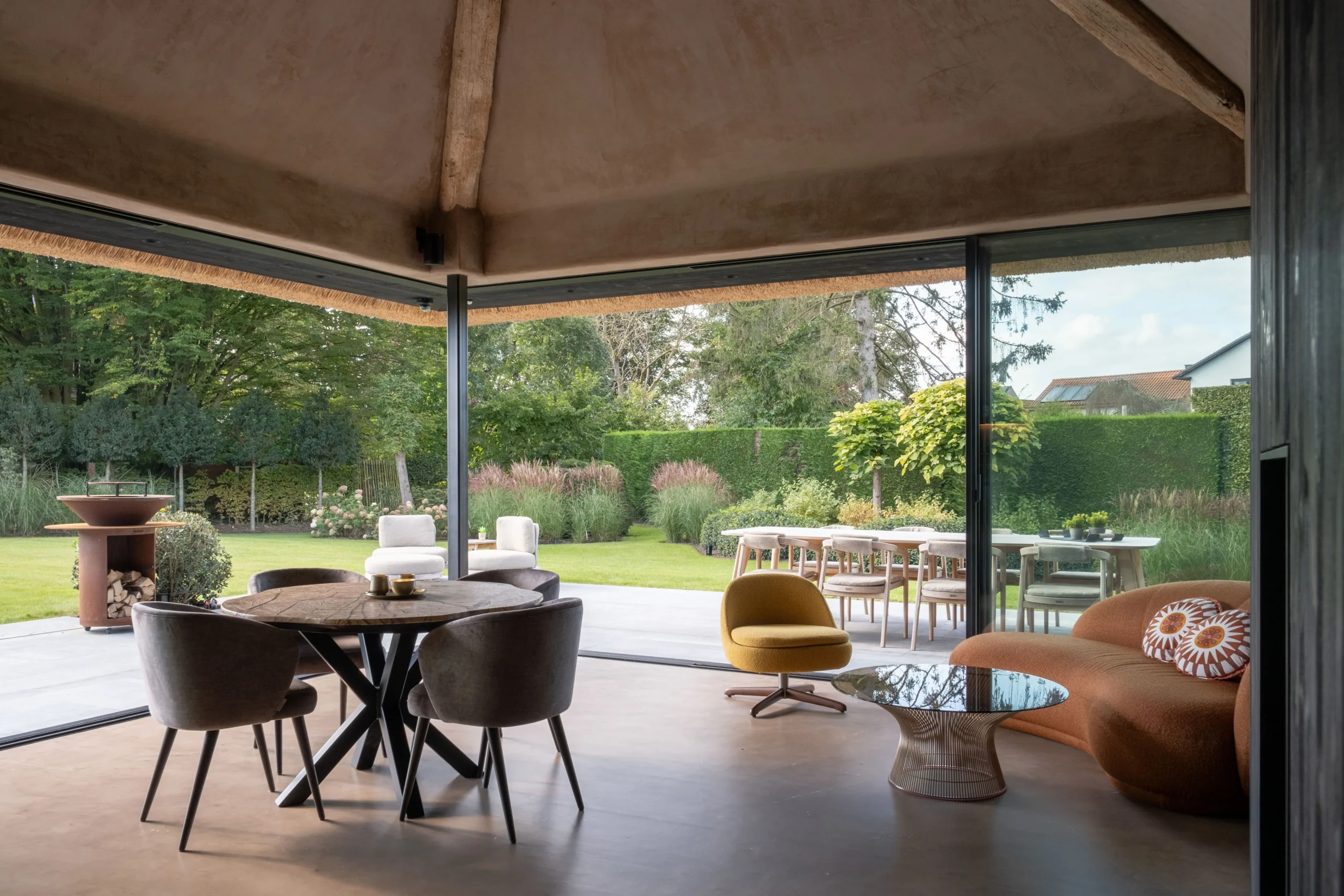 Binnenruimte met grote glaspartijen en uitzicht op de tuin.