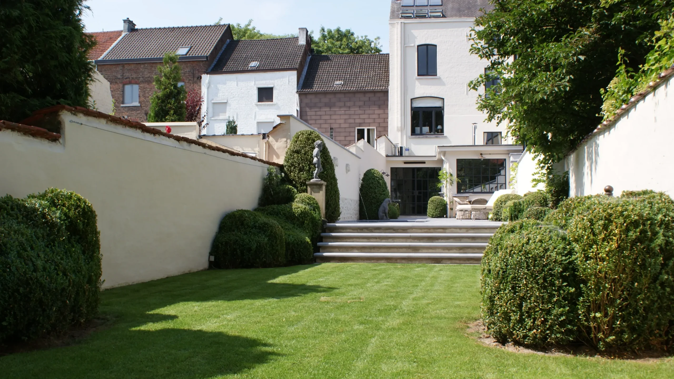 Tuin met trappenpartij, hagen en klassieke woning.