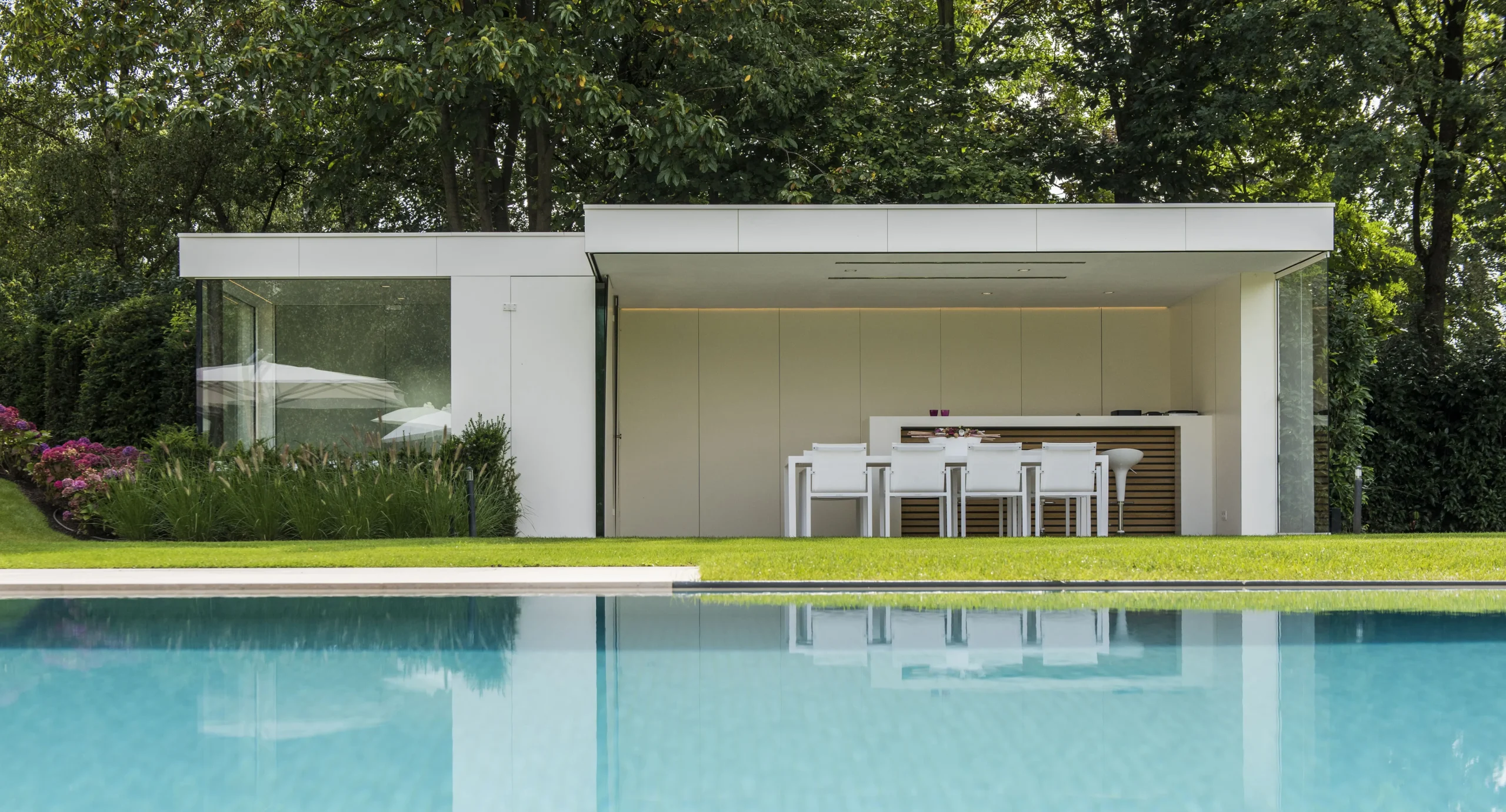 Poolhouse met open keuken en zicht op het zwembad.