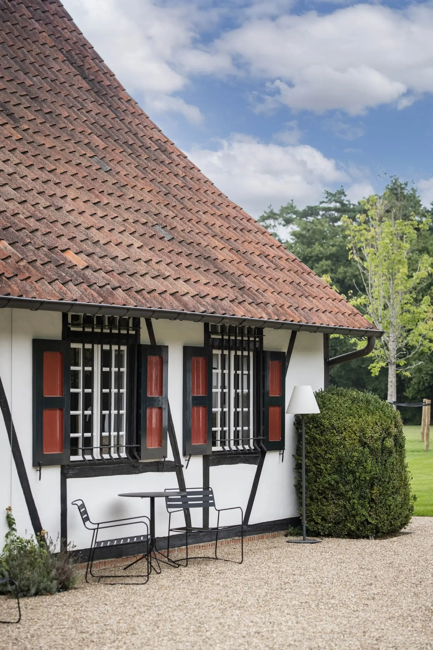 Authentieke hoeve met wit-rode gevel en landelijke tuin.