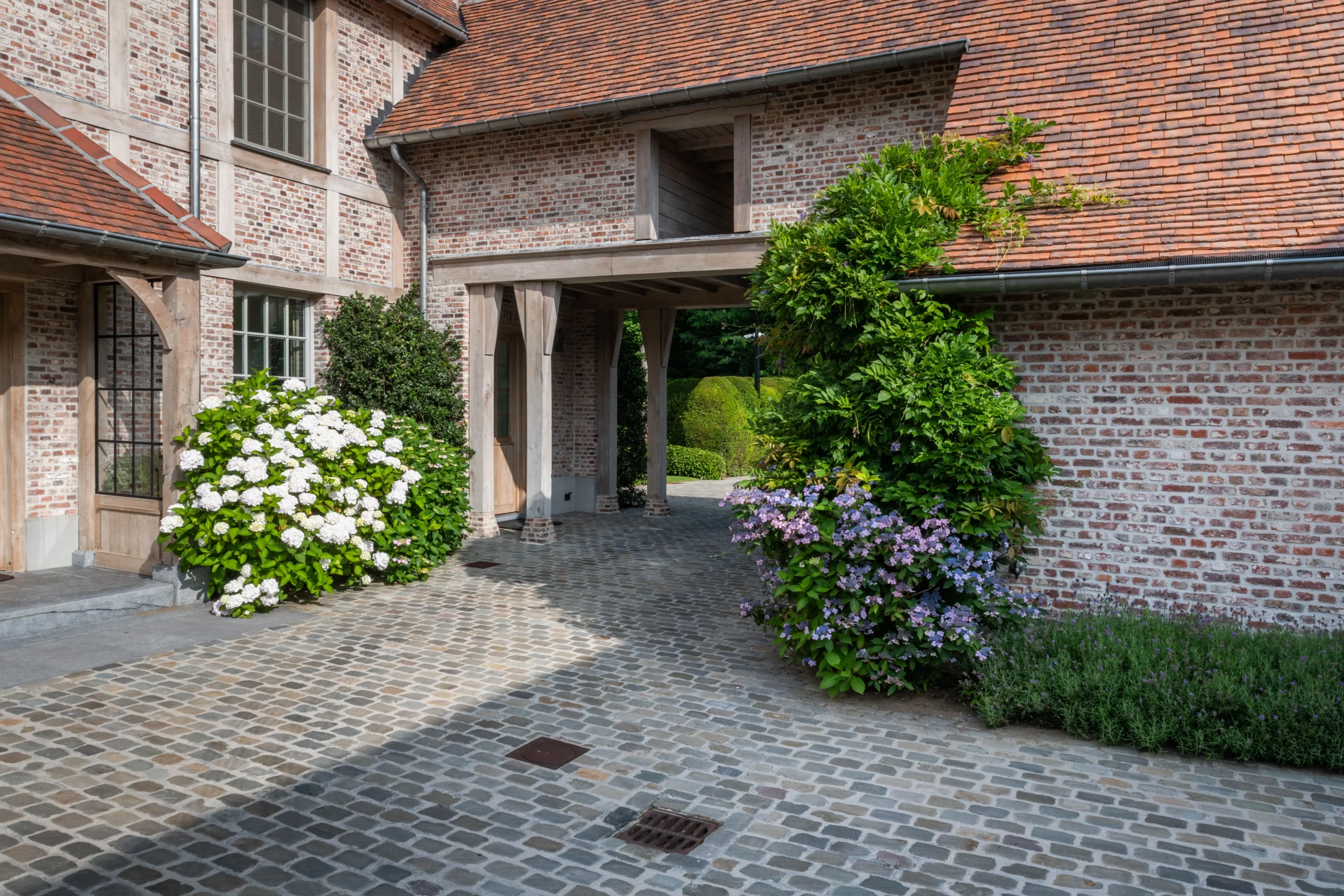 Binnenplaats met kasseien, hagen en klassieke architectuur.